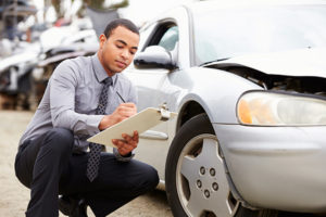 An insurance adjuster looking at the hood of a vehicle after an accident