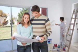 Homeowners standing in front of a painter looking over plans for their new addition
